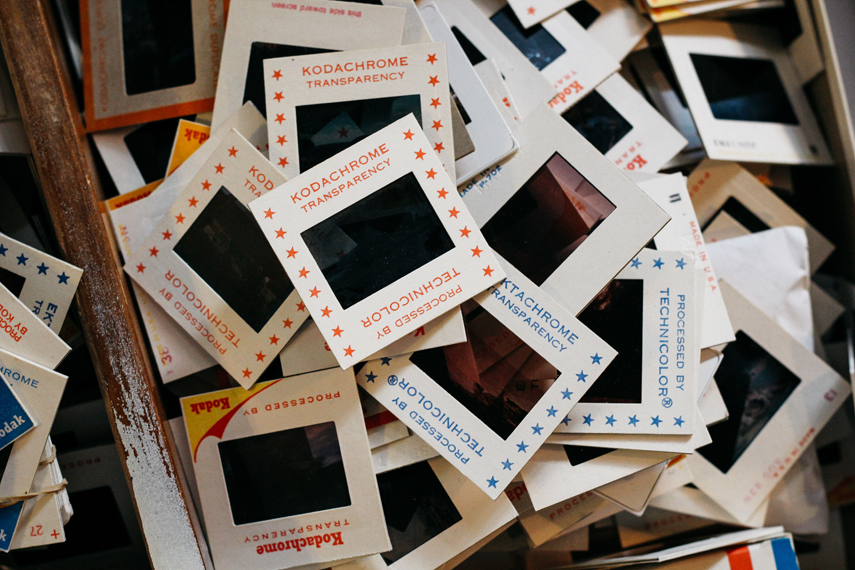 Dozens of Kodachrome film negatives are piled up in a wooden drawer, each of them protected by a white 'transparency' frame.